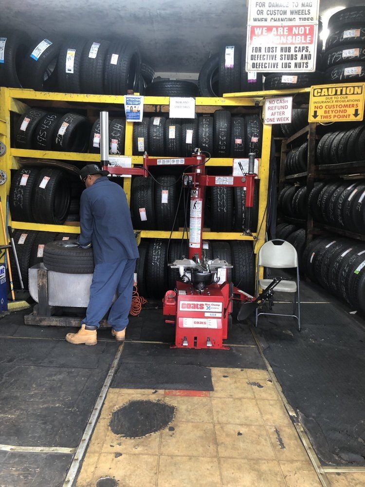 A mechanic at the tyre machine in Los Primos' bay, racks of tyres behind him